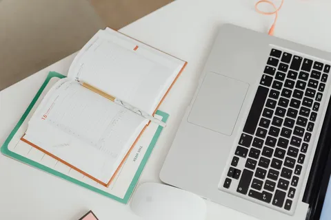 Top-down view of laptop and notebook planner on a clean desk
